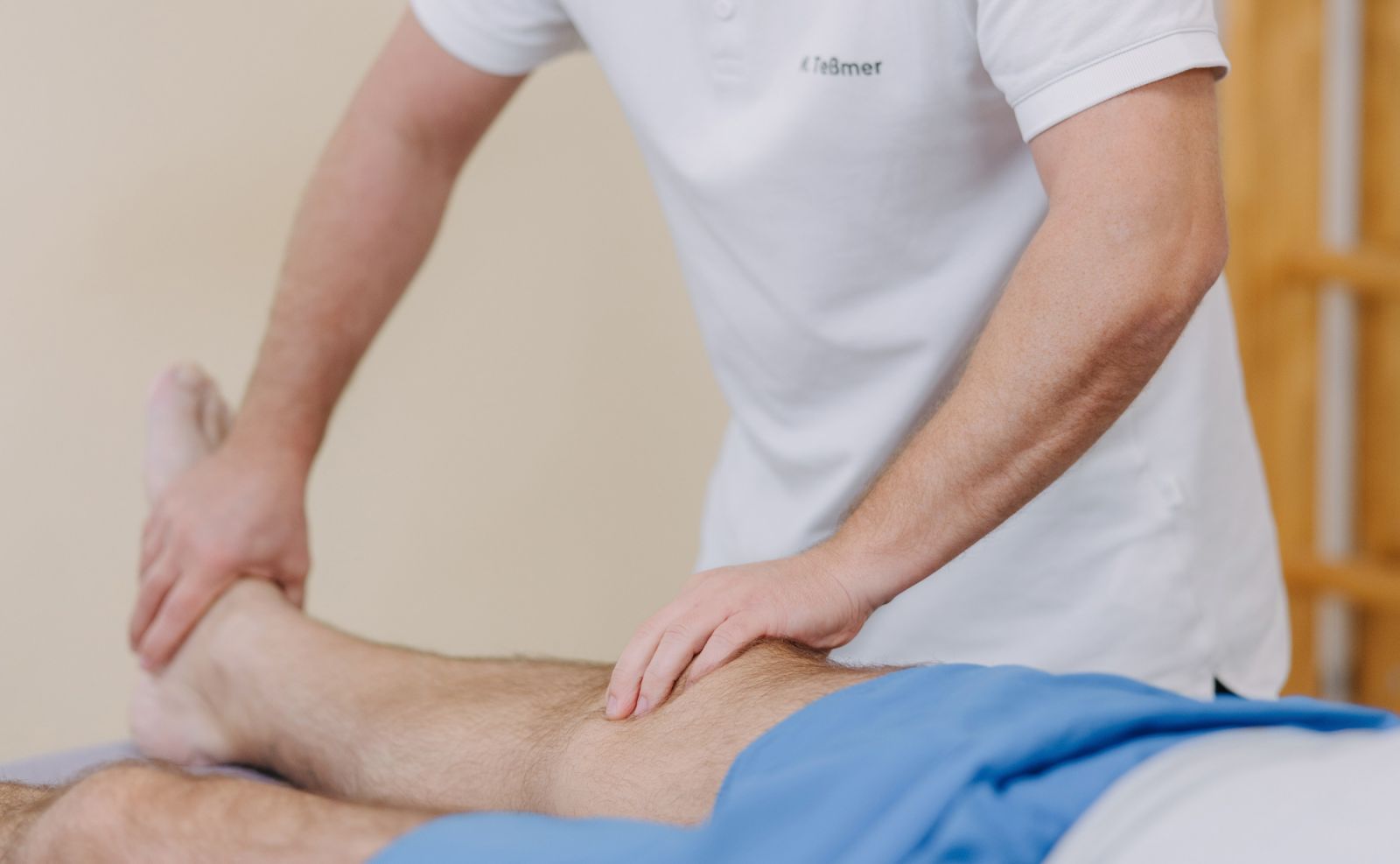 Sportphysiotherapeut behandelt einen Athleten bei einer Verletzung des Knies.